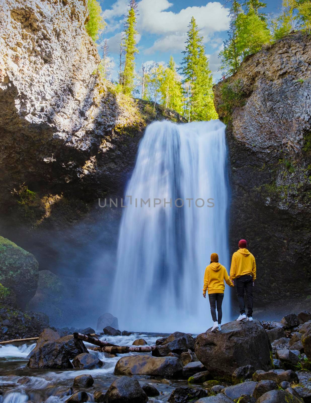 Moul Falls Canada is a Beautiful waterfall in Canada, couple of visits to Moul Falls, the most famous waterfall in Wells Gray Provincial Park. a couple of men and women standing by a waterfall