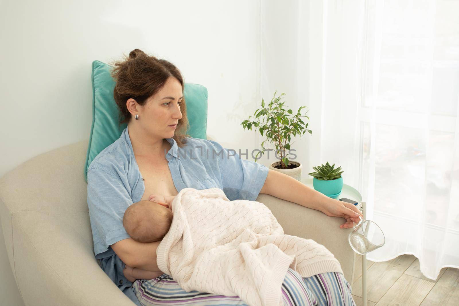 Woman drink water during process of breastfeeding of newborn baby. Comfortable and supported breastfeeding