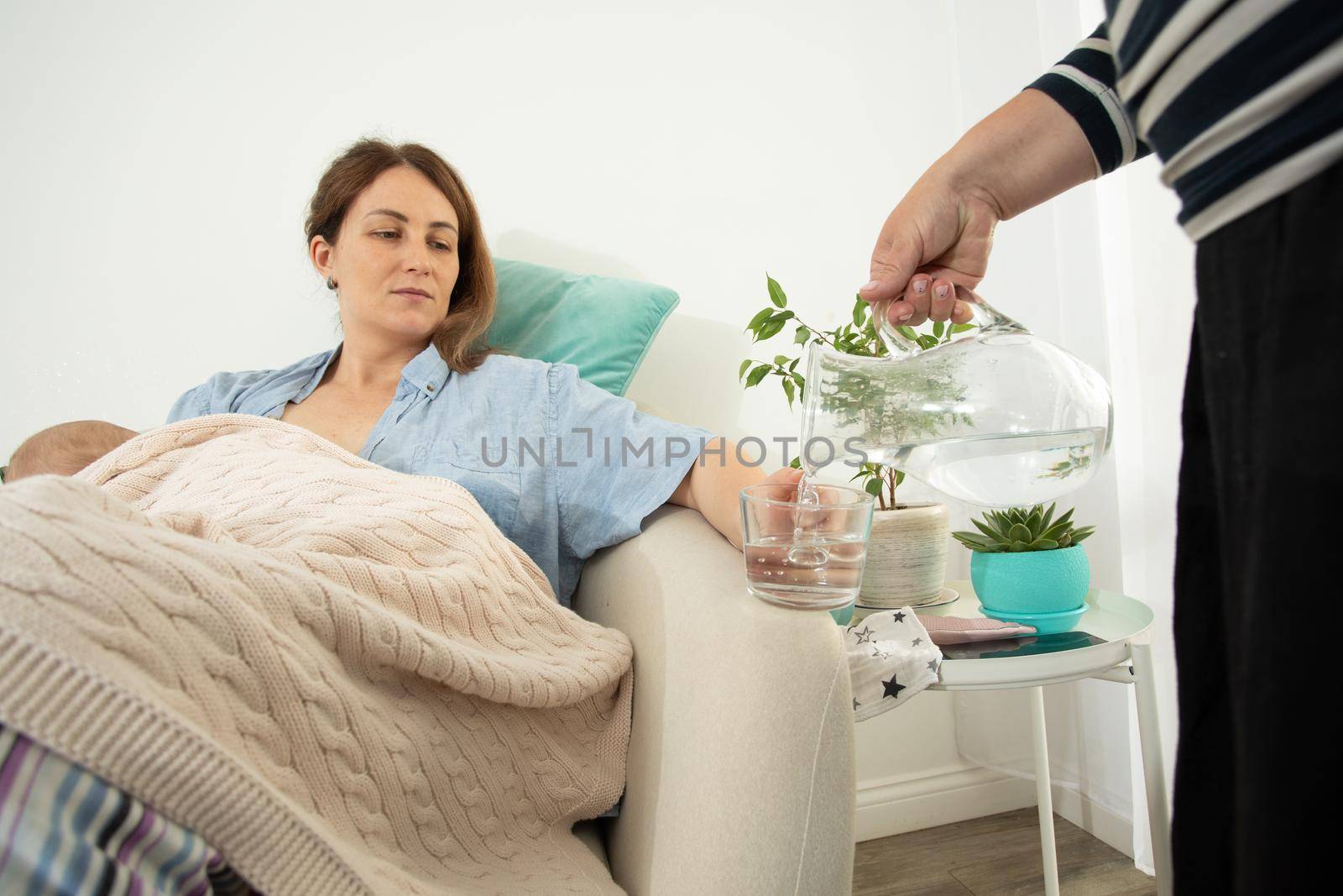 Woman drink water during process of breastfeeding of newborn baby. Comfortable and supported breastfeeding