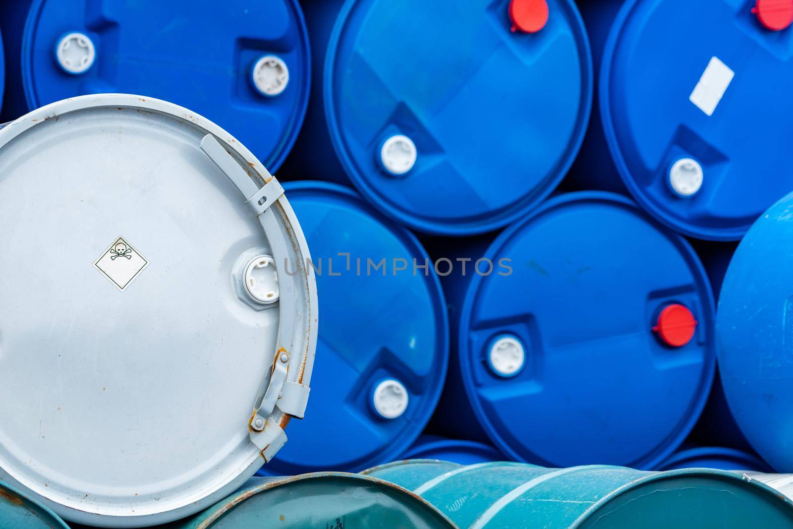Old chemical barrels. Blue and green oil drum. Steel and plastic oil tank. Toxic waste warehouse. Hazard chemical barrel with warning label. Industrial waste in drum. Hazard waste storage in factory. 