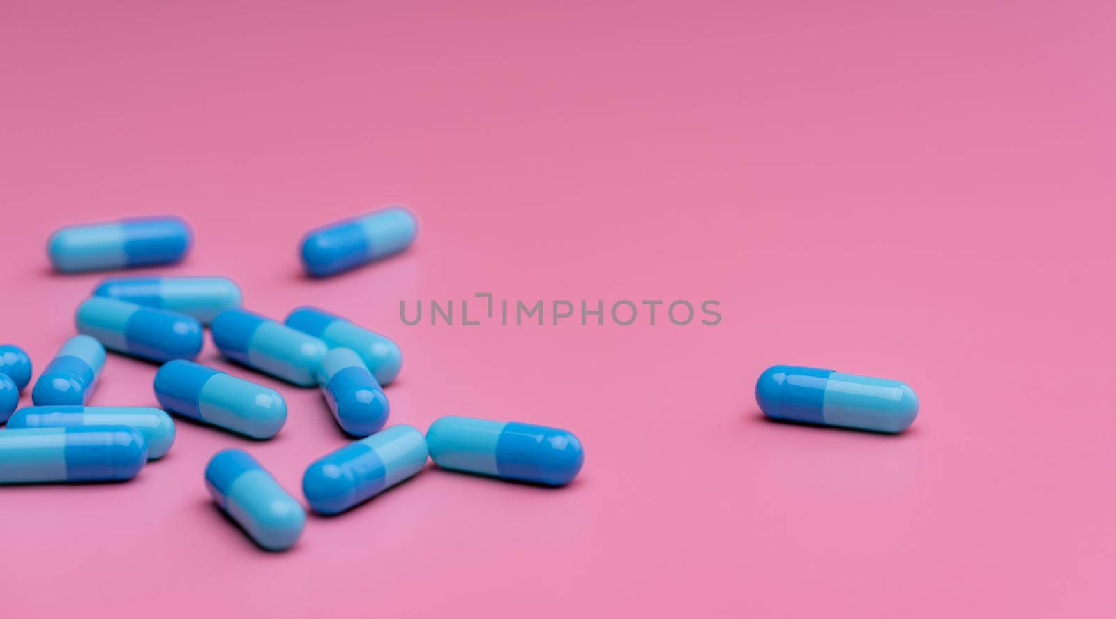 Blue capsule pills on pink background. Prescription drug. Pharmaceutics. Pharmaceutical industry. Pharmaceutical care. Healthcare and medicine. Drug related problems. New drug research and development by Fahroni