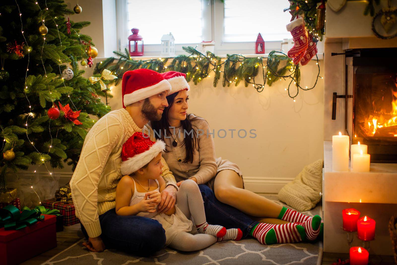 happy family father mother and children sitting by fireplace on Christmas Eve by oksix