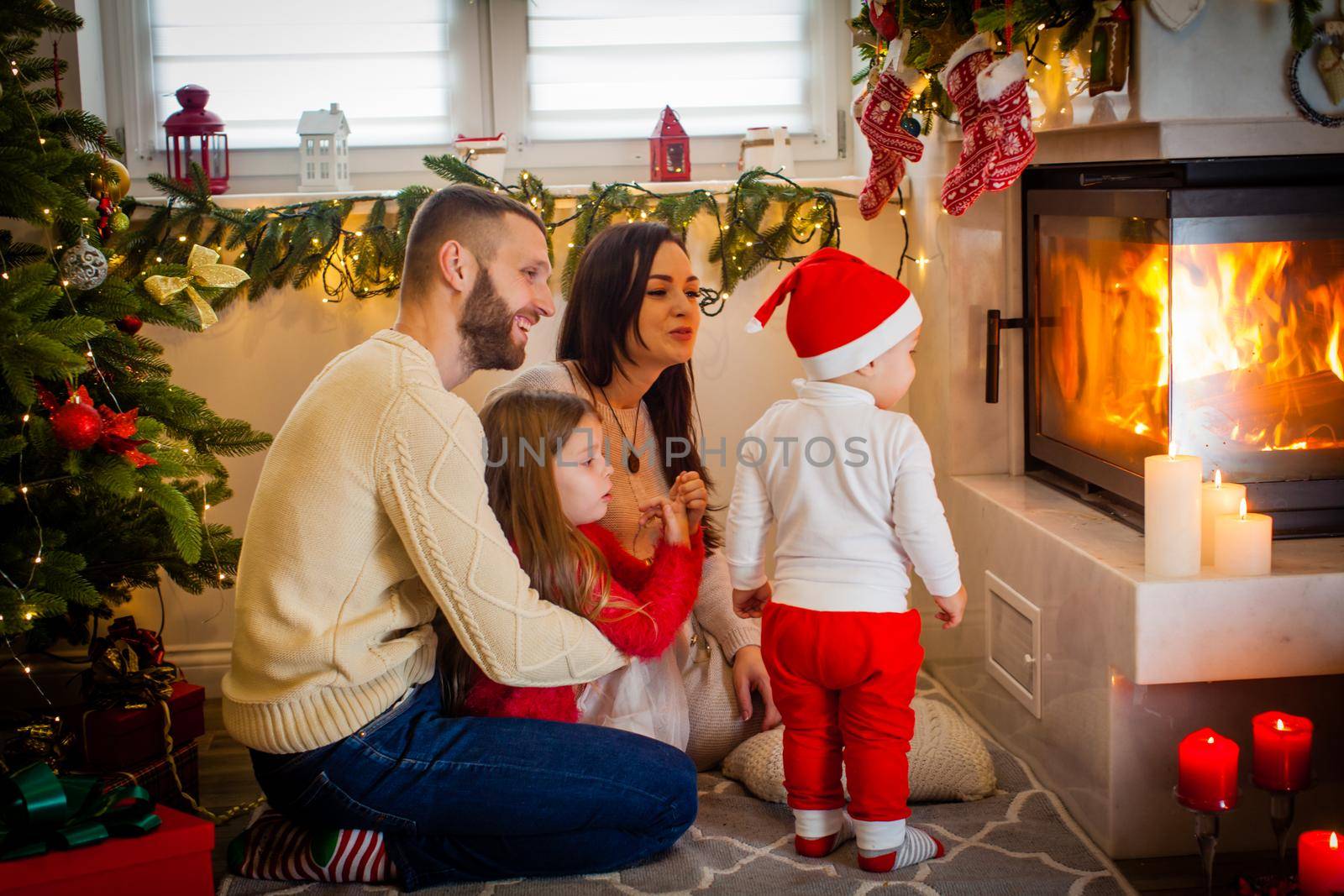 happy family father mother and children sitting by fireplace on Christmas Eve by oksix