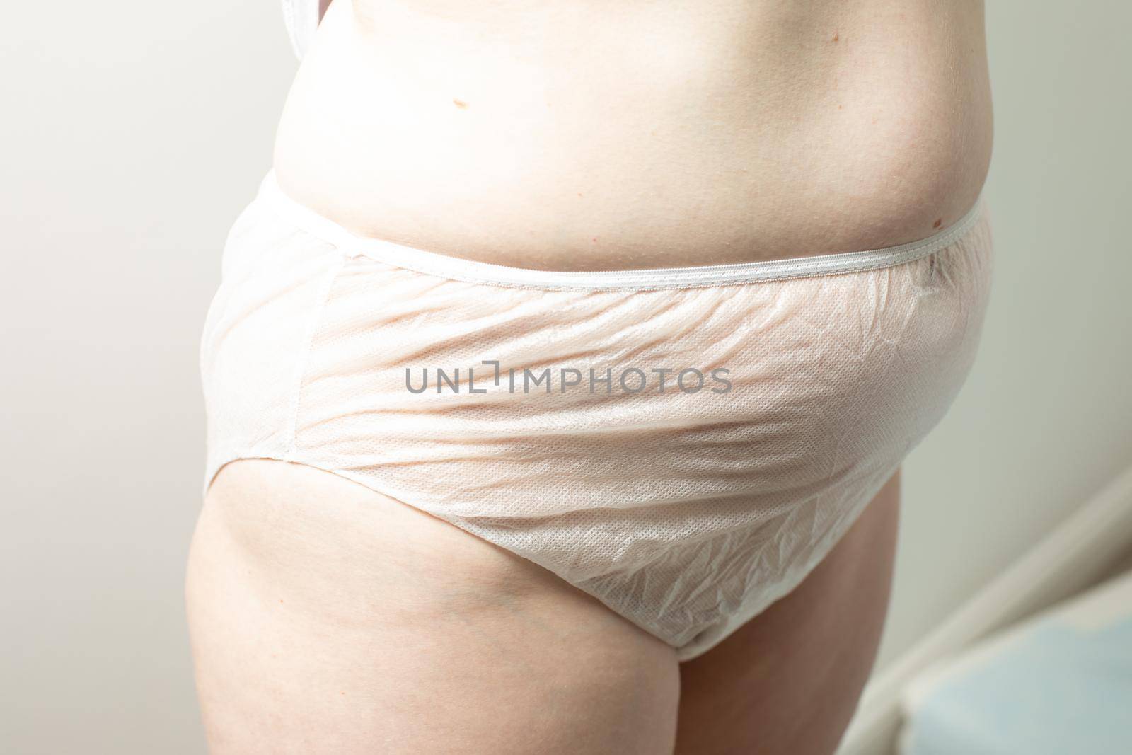 Female postpartum belly in disposable underpants, hygiene by oksix