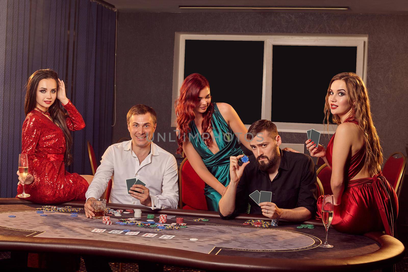 Group of a young rich friends are playing poker in casino. by nazarovsergey
