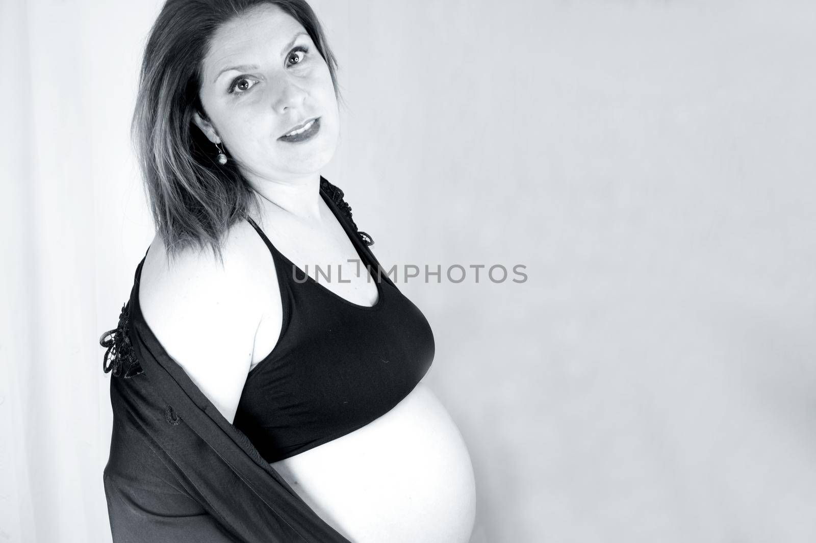 Eight month pregnant woman with bare belly. Happy emotion