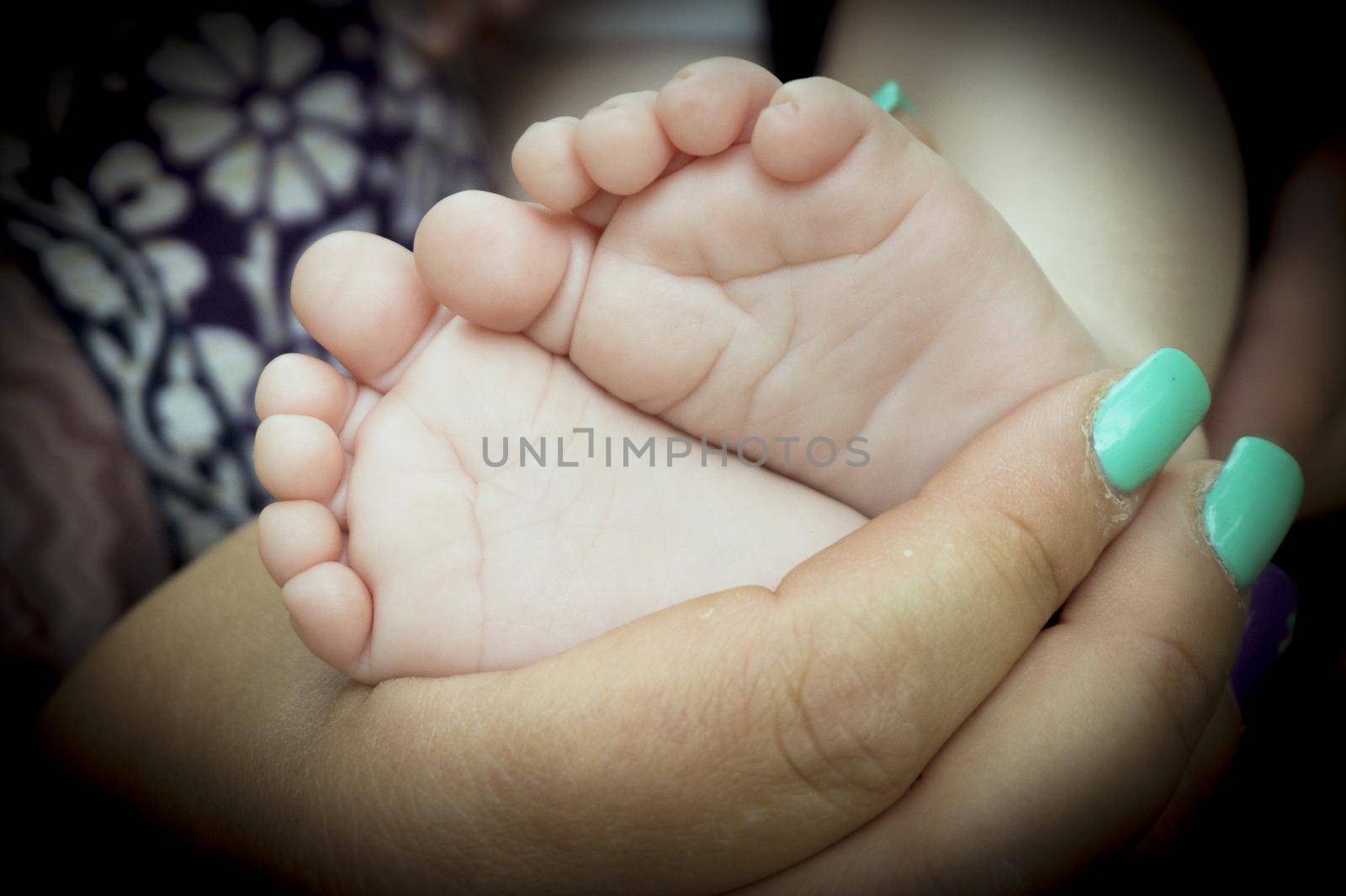 Baby feet held by mothers hand. Black background