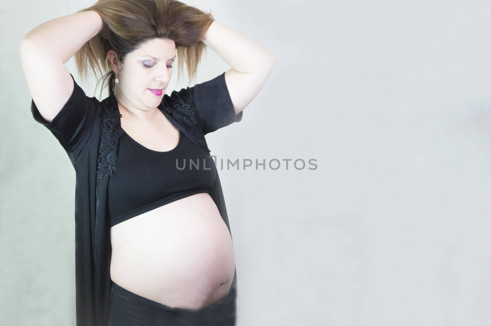 Eight month pregnant woman with bare belly. Happy emotion