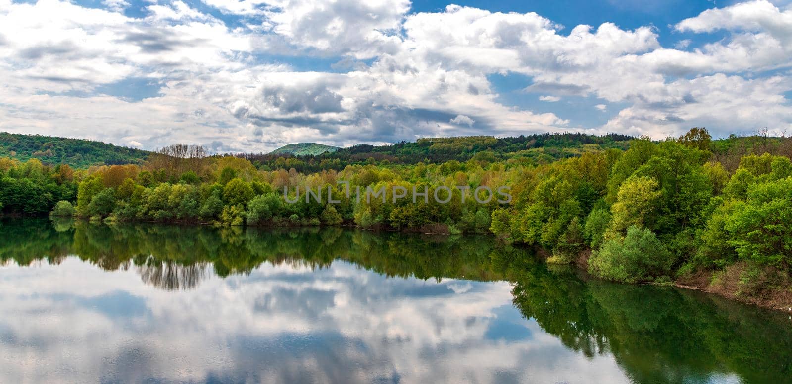 Landscape at the lake with calm water, trees reflection, and beautiful sky