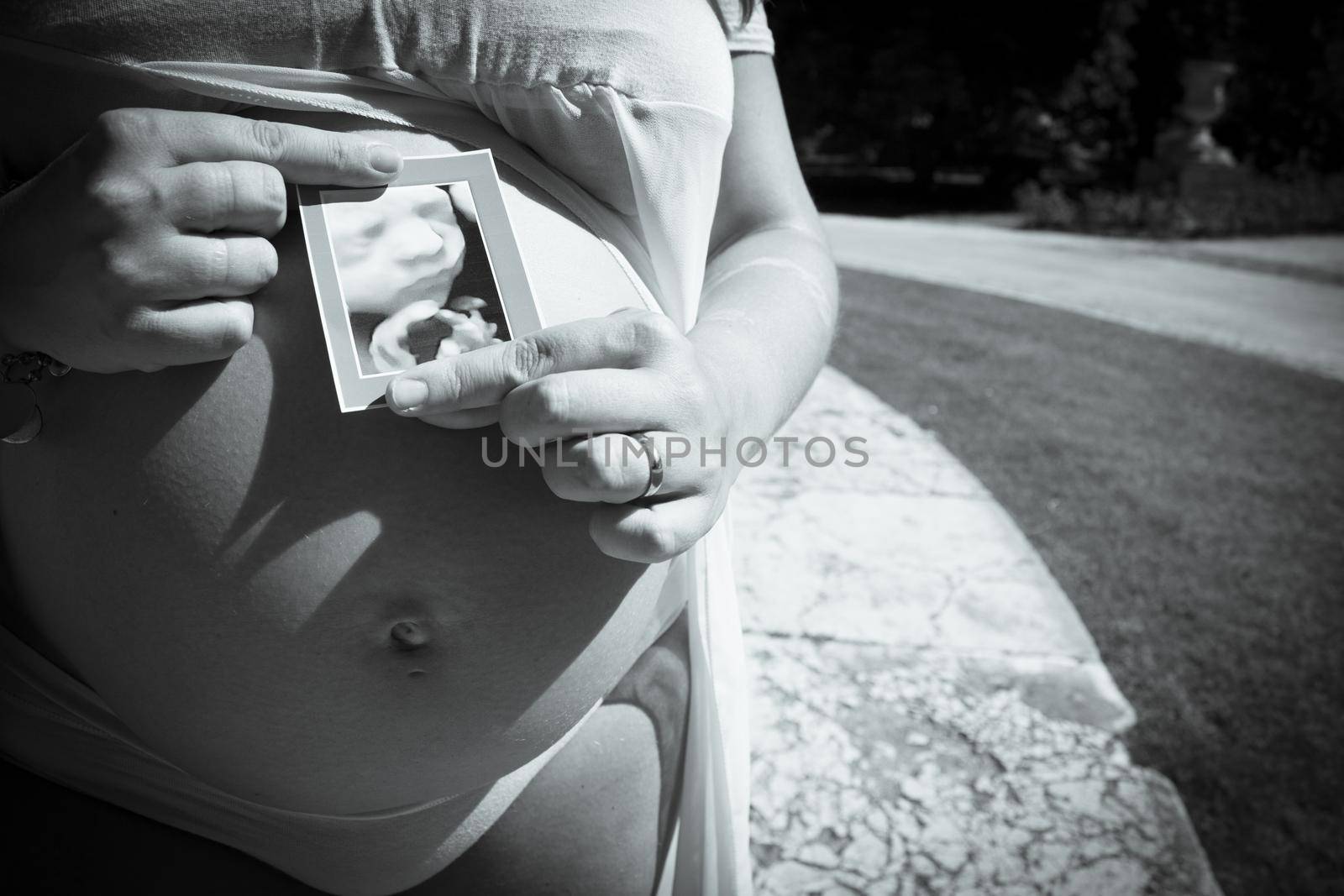 Seven month pregnant woman with ultrasound of baby on her gut. Pink dress color