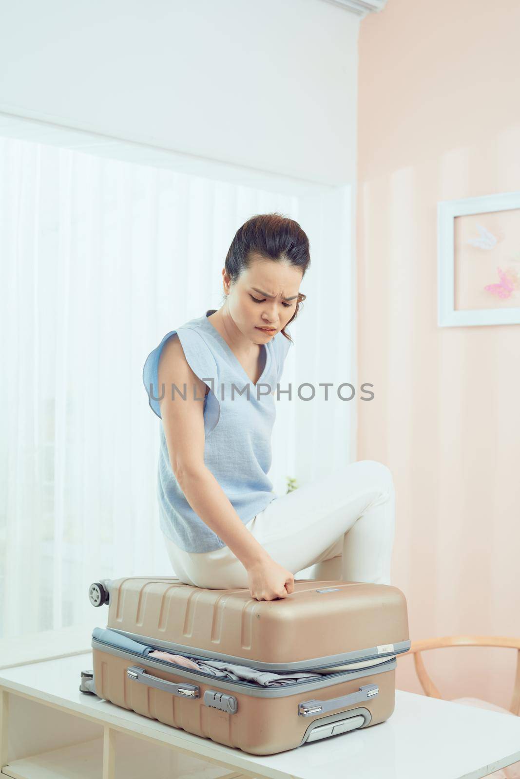 A picture of a woman having problem with packing a suitcase