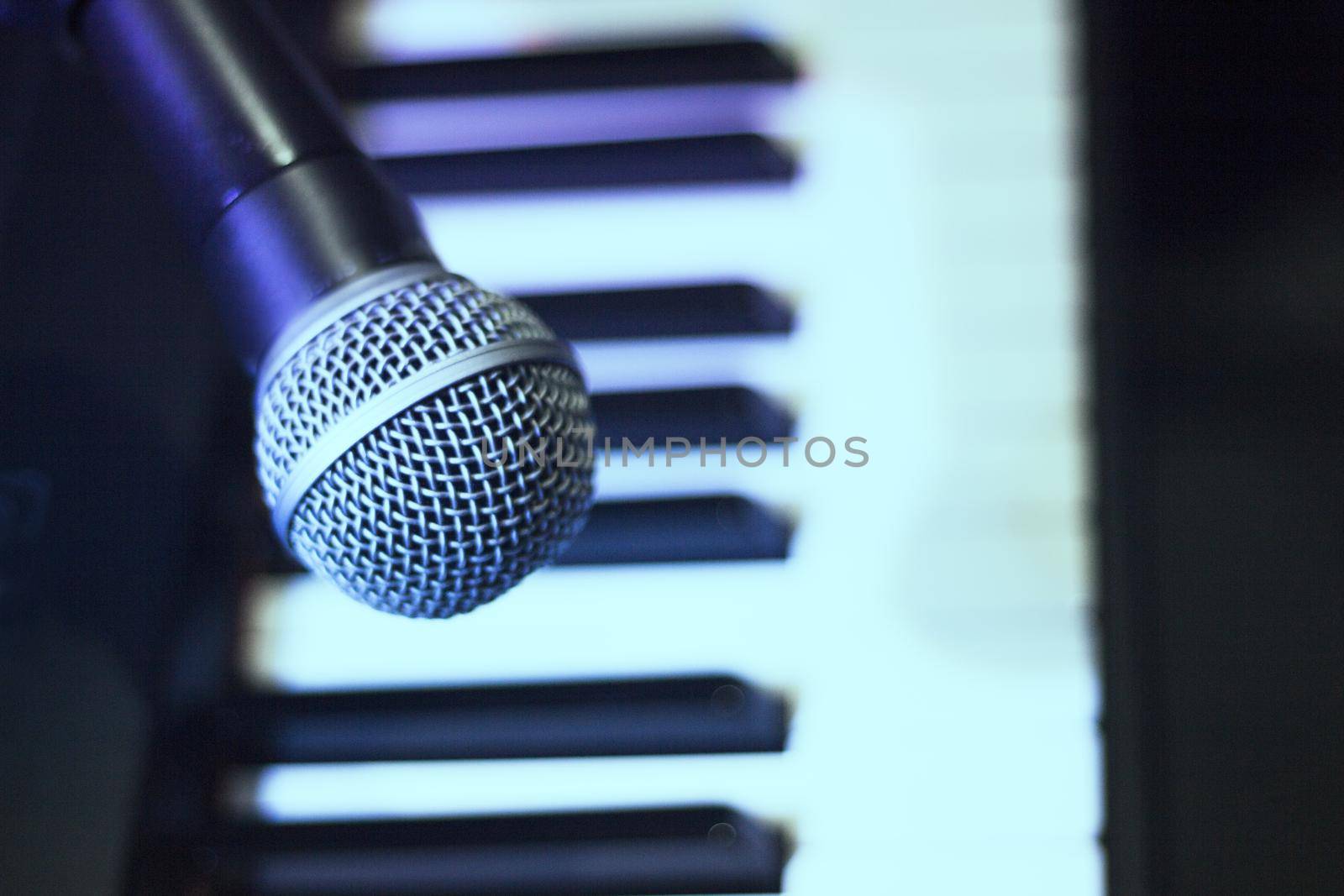 Microphone over piano keys in dim light. No people