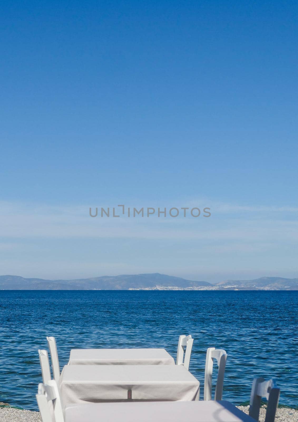 White restaurant tables on the beach in summer - travel, vacation and summer concept. The perfect lunch with a sea view