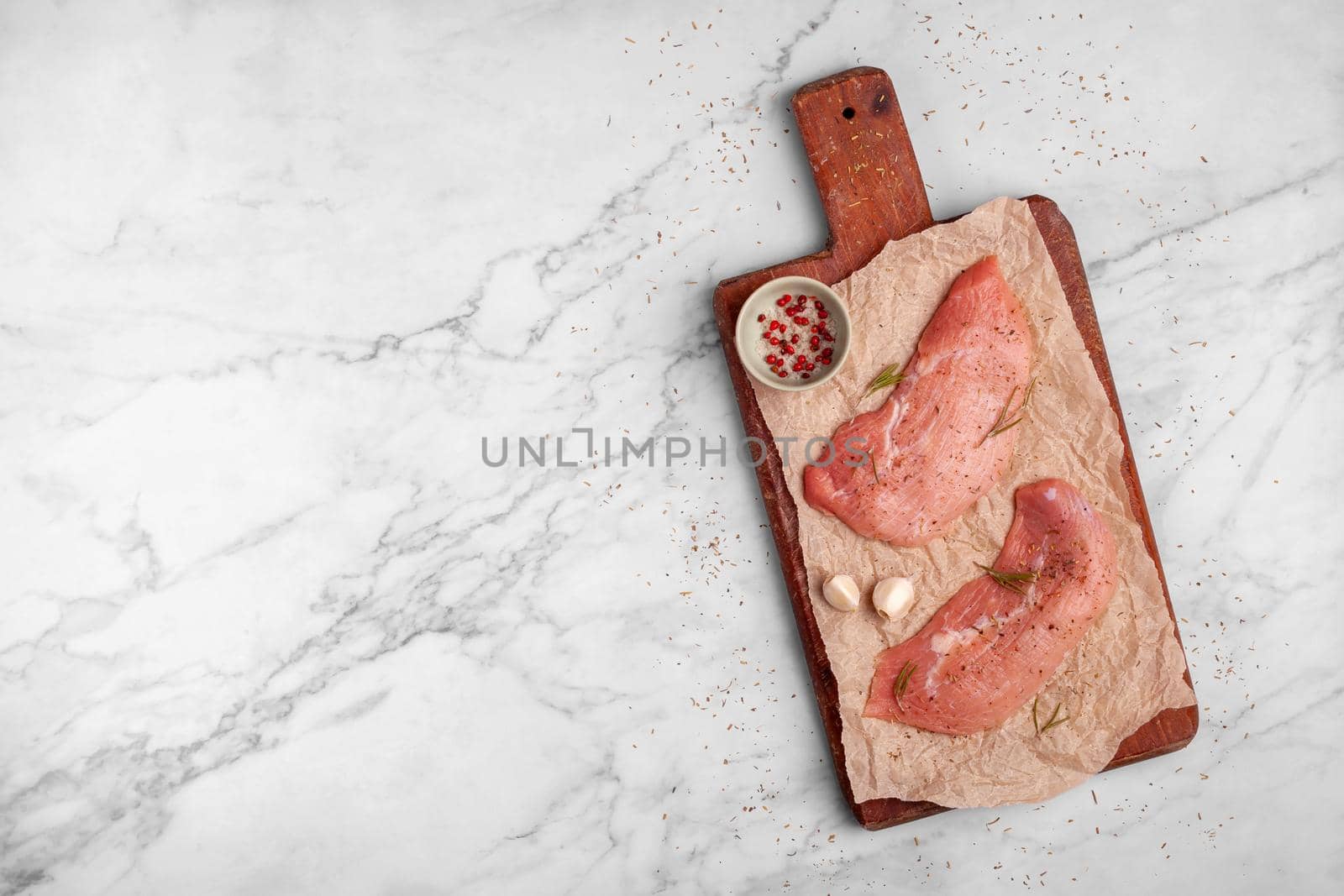 two raw veal escalope on the old wooden cutting board, ready to cook, marbre background, top view, copy space