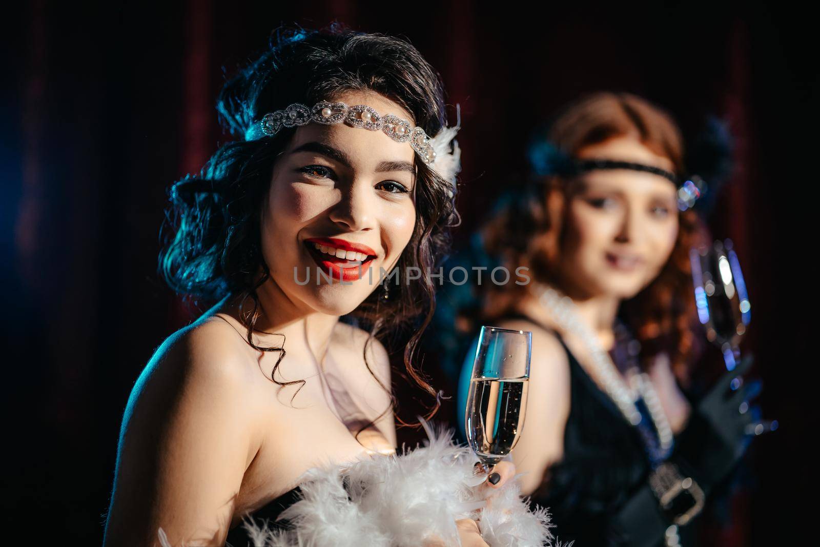 Portrait of young flapper women dressed in style of Great Gatsby posing on dark velours background. Roaring twenties, retro, party, fashion concept by kristina_kokhanova