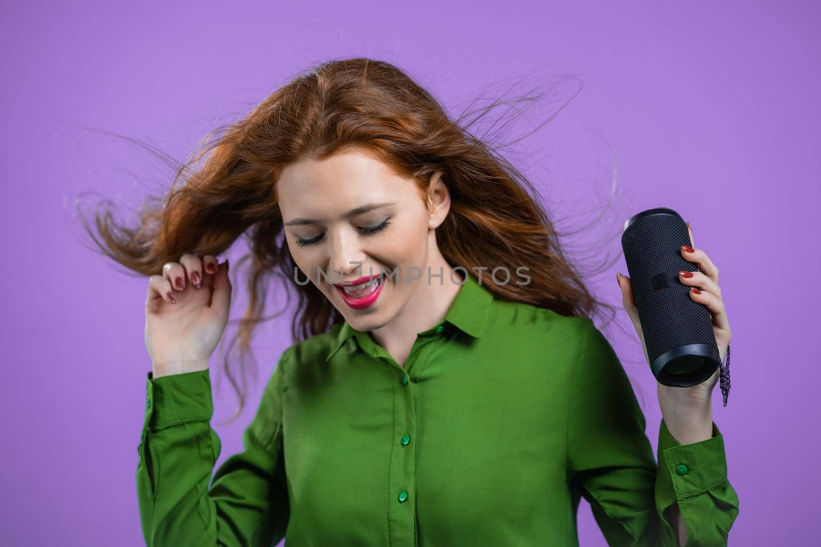 Woman listening to music by wireless portable speaker - modern sound system. Lady dancing, enjoying on violet studio background. She moves to the rhythm of music. by kristina_kokhanova