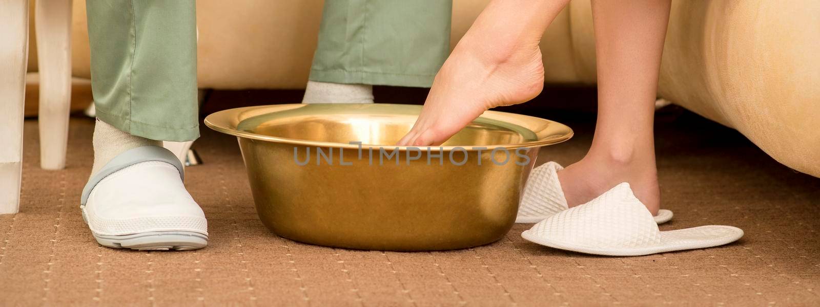 A woman is dipping feet in a bowl before washing feet therapy