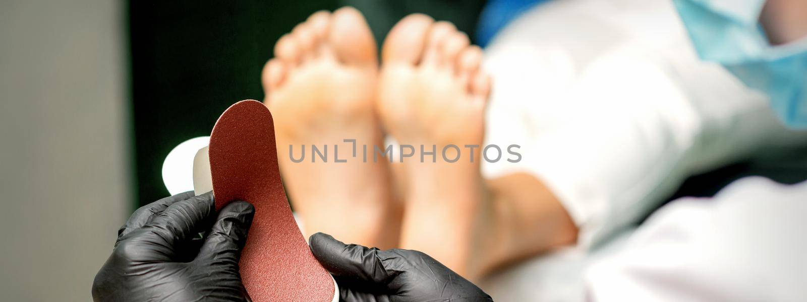 The pedicurist put on a new heel file on the metal handle before the procedure of cleaning the feet in a nail salon