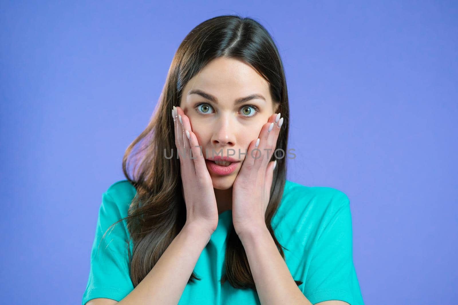 Portrait of unpleasantly surprised and shocked girl on violet studio background. Woman receiving bad news. She expresses sympathy and regret. High quality photo