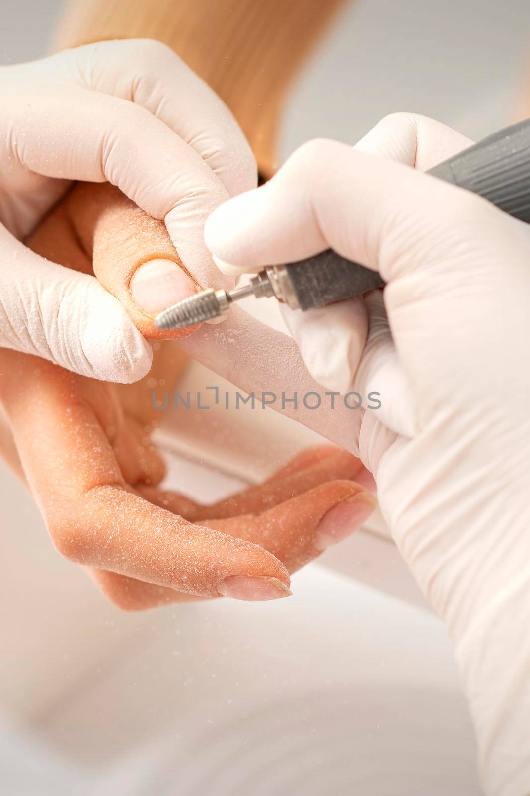 Closeup of manicure master removes nail polish uses an electric nail file in a nail salon