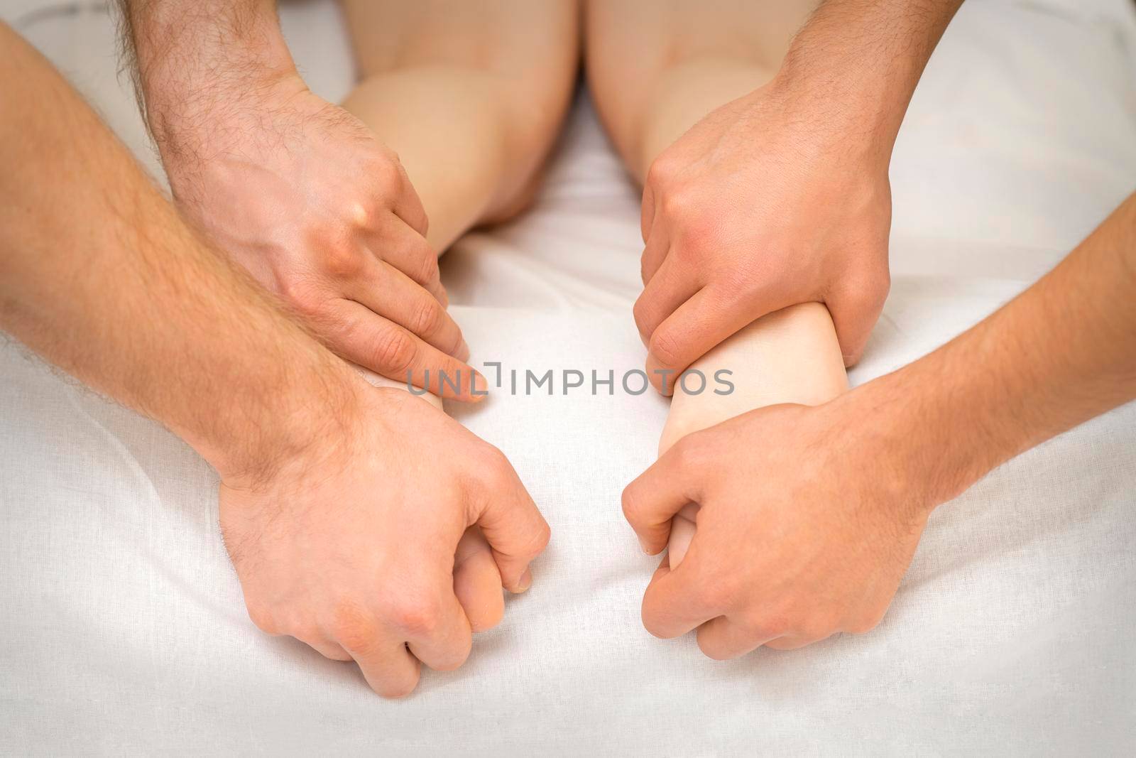 Closeup of young female receiving foot massage in four hands in a spa