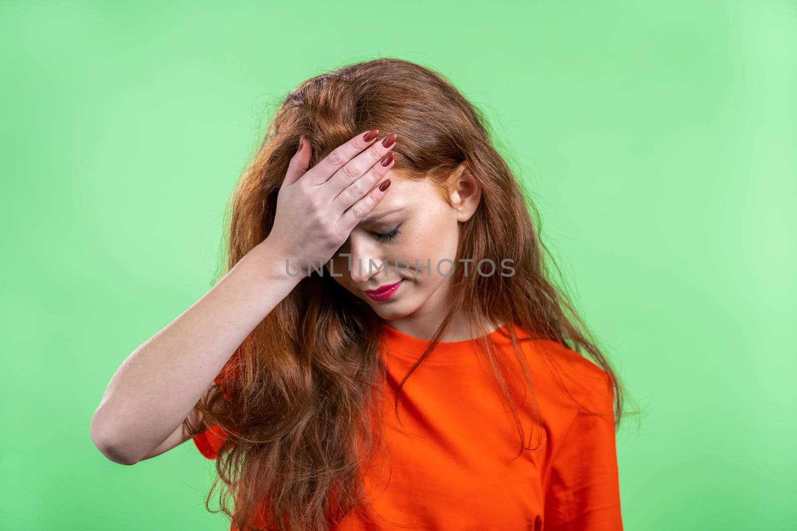 Portrait of young woman doing facepalm gesture, like no, I forgot. Unhappy woman feeling sorrow, regret, drama, failure. She isolated on green wall. High quality photo