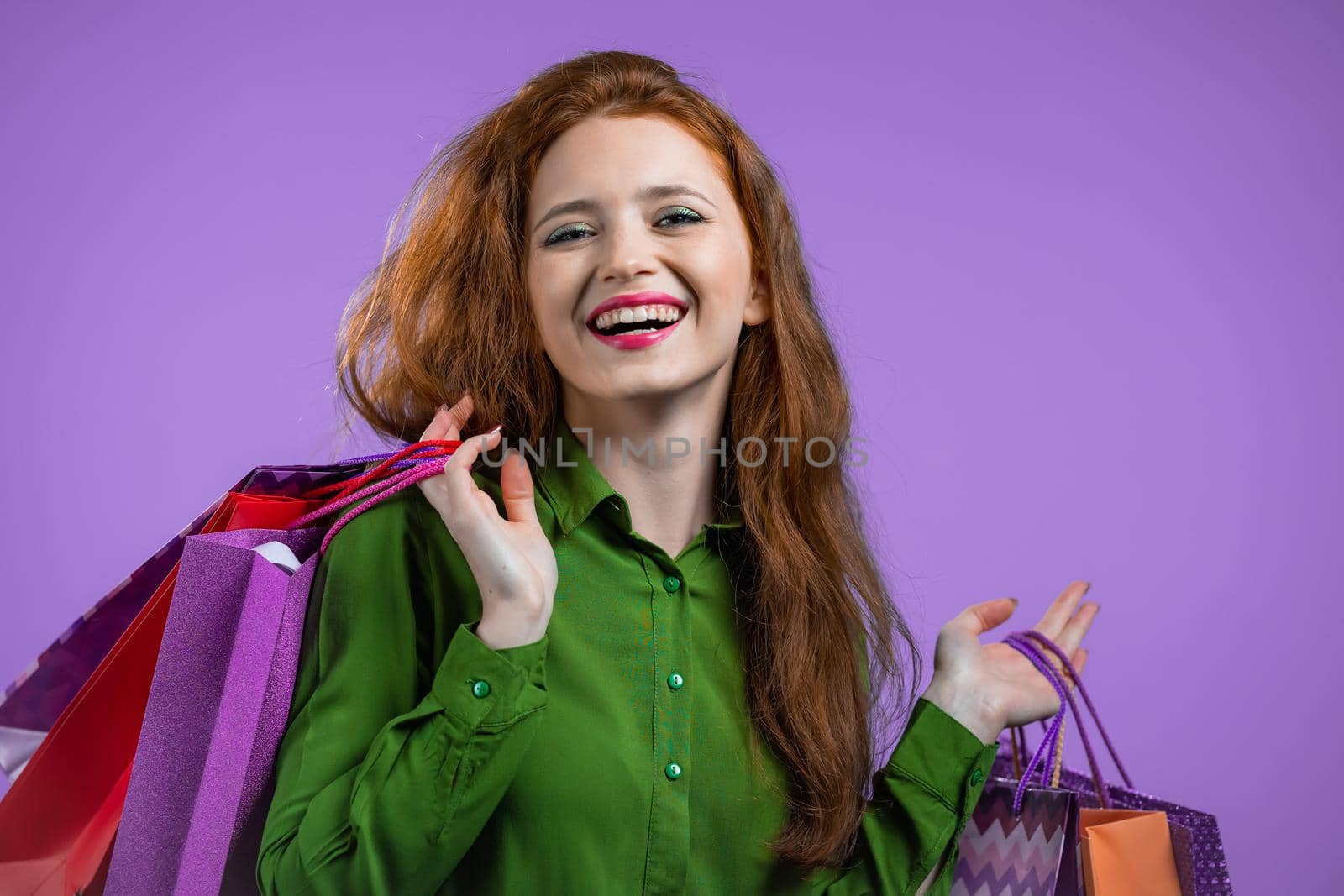 Excited woman with colorful paper bags after shopping on violet studio background. Concept of seasonal sale, purchases, spending money on gifts. High quality photo