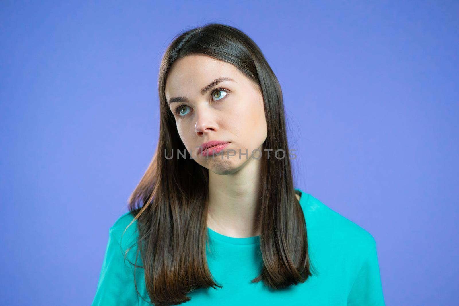 Portrait of girl, she exhales from heat or stuffiness. Heatstroke concept. Violet studio. Young tired woman is dissatisfied, unhappy. High quality photo