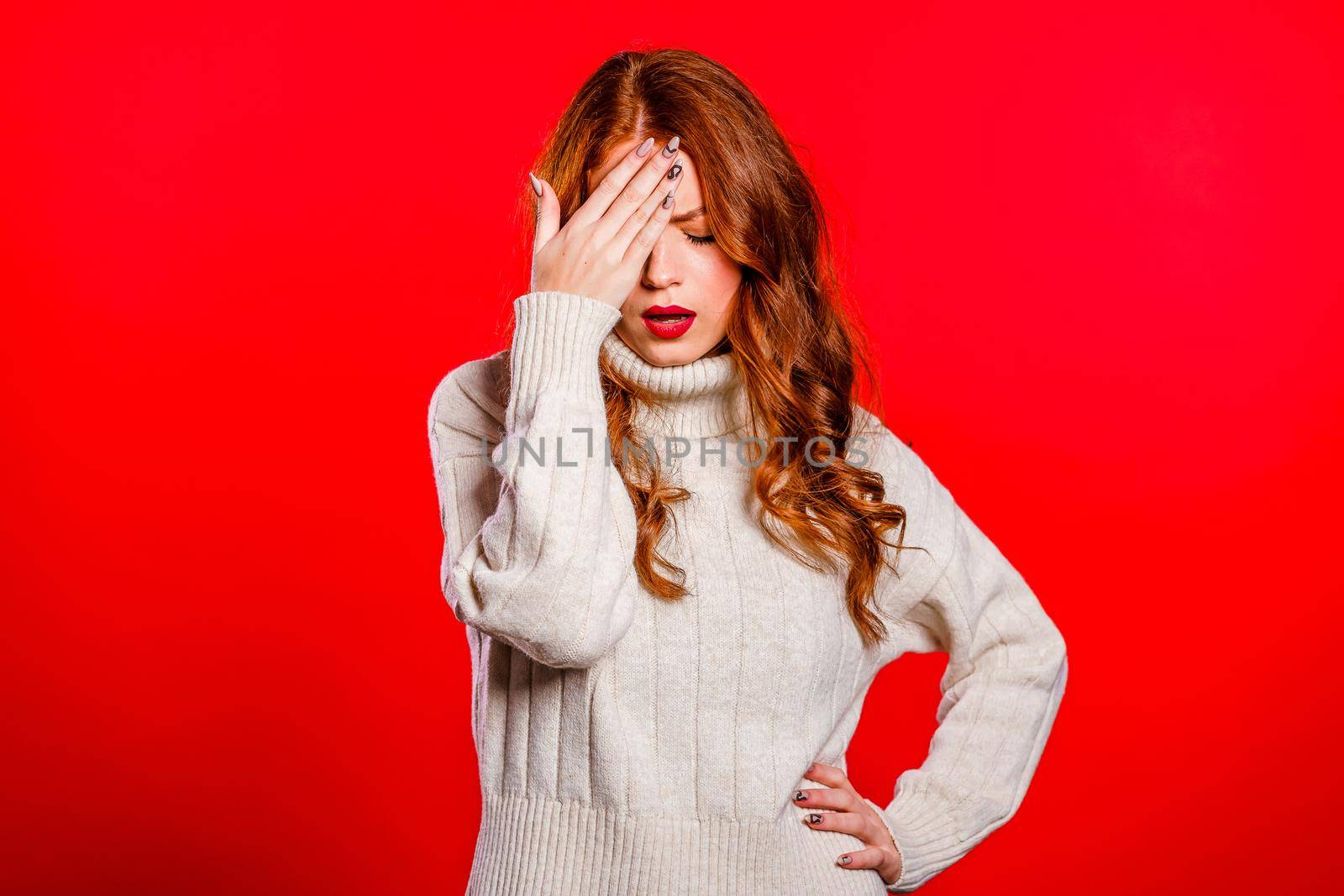 Portrait of forgetful woman. Pretty girl holding hand on head like gesture of bad memory. Red studio background