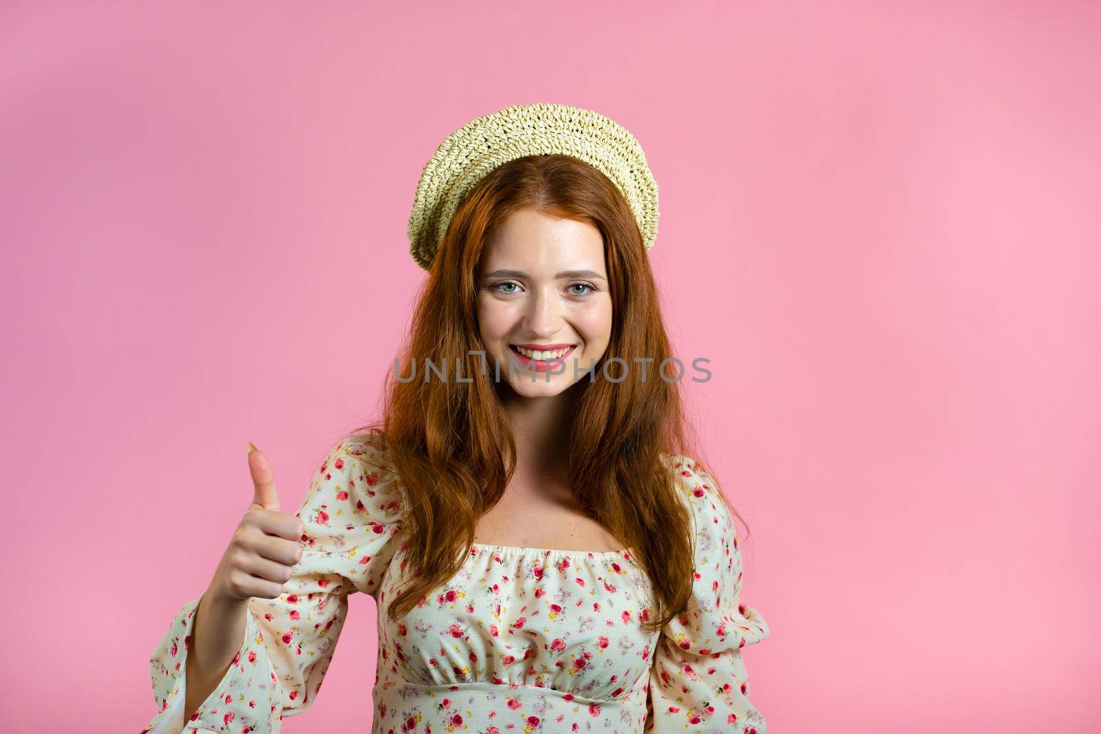 Lady with long hair shows thumbs up, Like gesture. Happy woman on pink background. Winner. Success. Positive girl smiles to camera. Body language