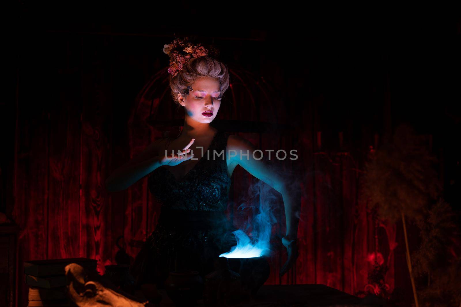 Halloween Witch with cauldron. Beautiful young woman conjuring, making witchcraft by andreonegin