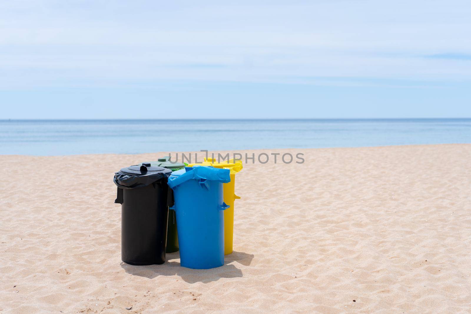 Clean beach garbage bins. Multi colored garbage containers for separate collection of garbage stand on empty beaches near the ocean