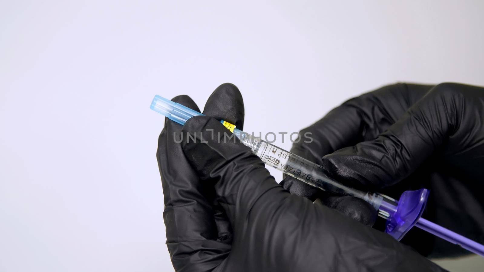 close-up, a sterile syringe with hyaluronic acid in the hands of a doctor dressed in black gloves. High quality photo