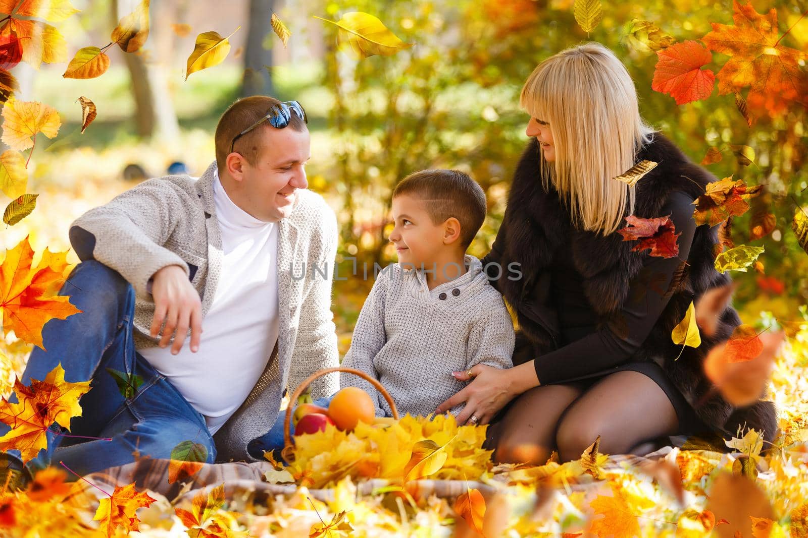 family, childhood, season and people concept - happy family playing with autumn leaves in park by Andelov13