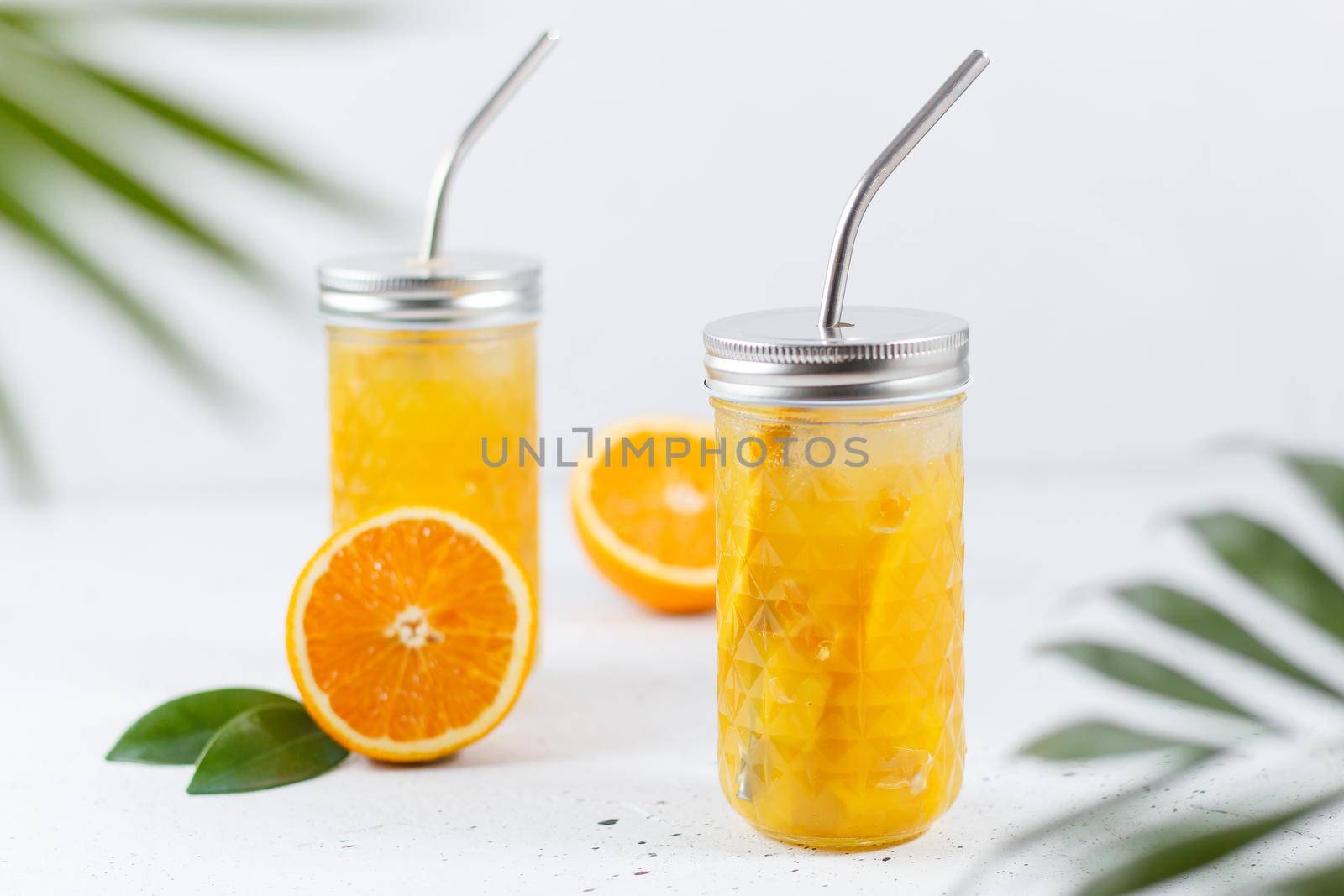 Glasses with orange juice, orange slices and mango on a gray background.