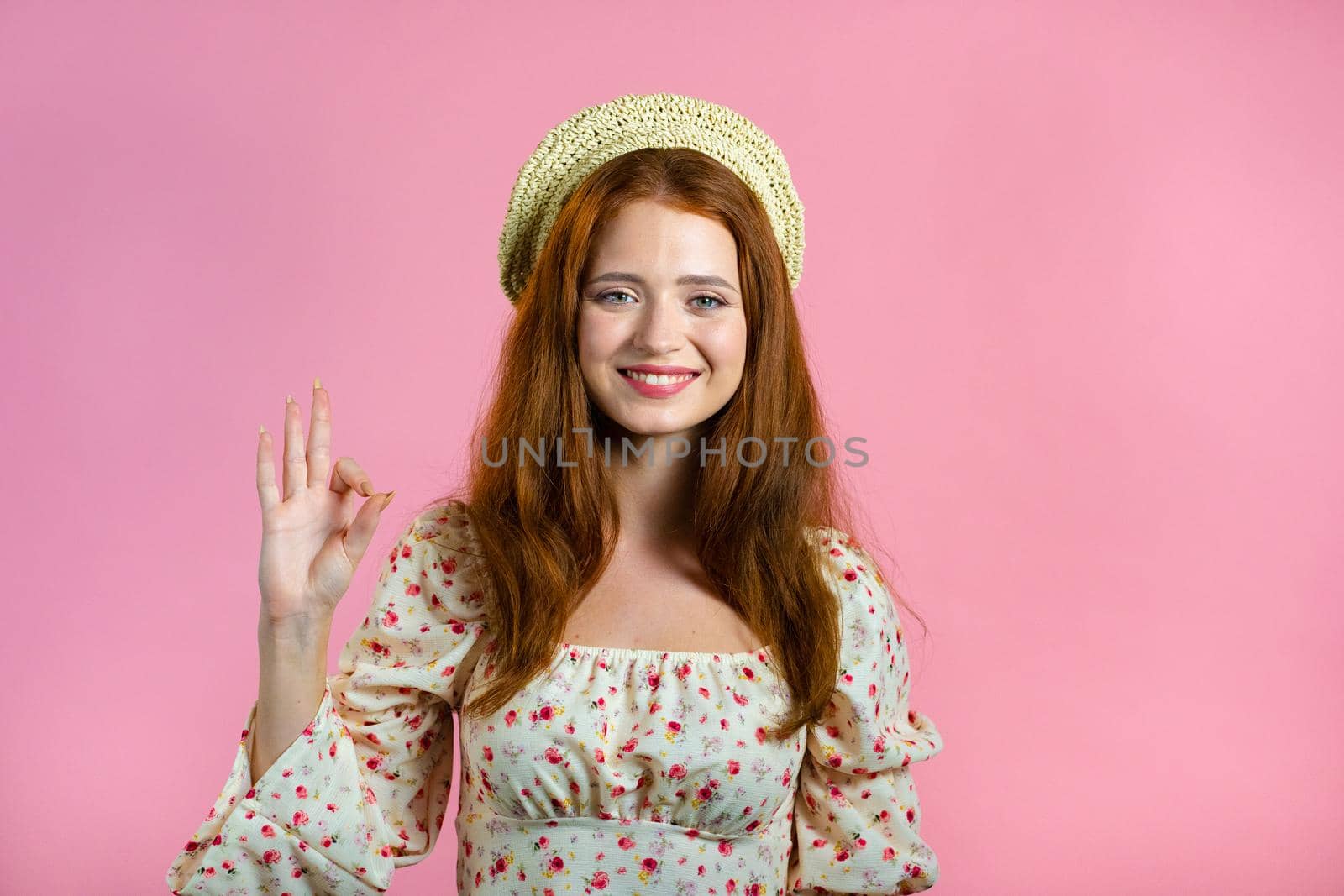 Cute woman showing thumb up sign over pink background. Positive young girl smiles to camera. Winner. Success. Body language. High quality photo