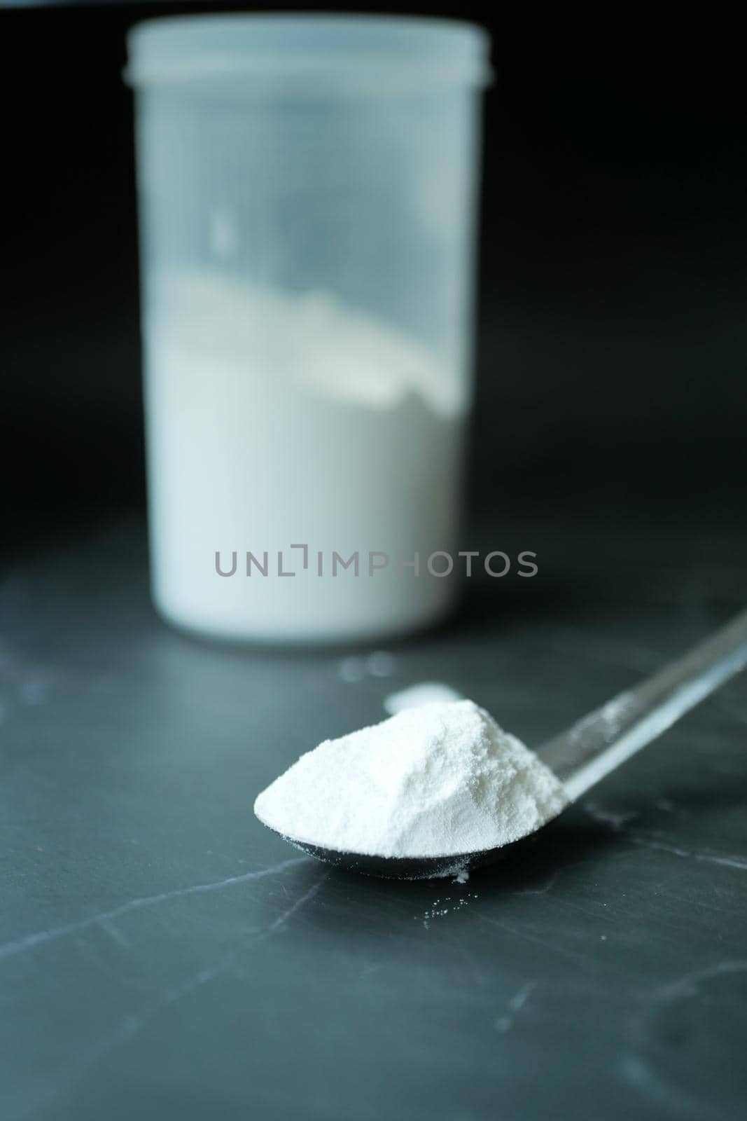 Washing powder in plastic spoon on black background ,