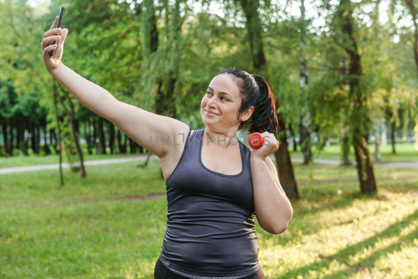 A charming brunette woman plus-size body positive practices sports in nature.