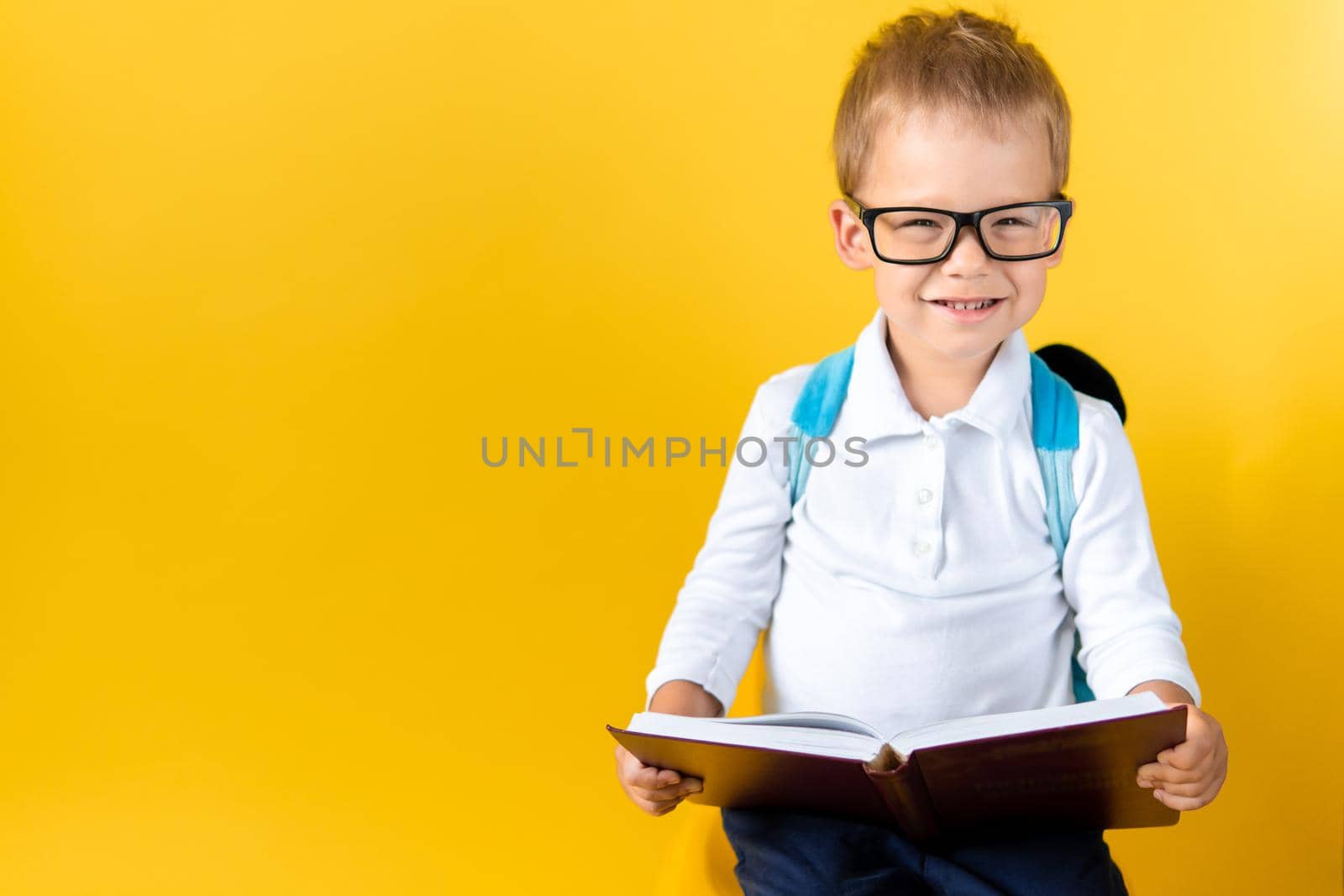 Banner Funny Preschool Child Boy in Big Glasses Reads Book on Yellow Background Copy Space. Happy Smiling Kid Go Back to School, Kindergarten. Success, Motivation, Winner, Genius, Superhero concept.