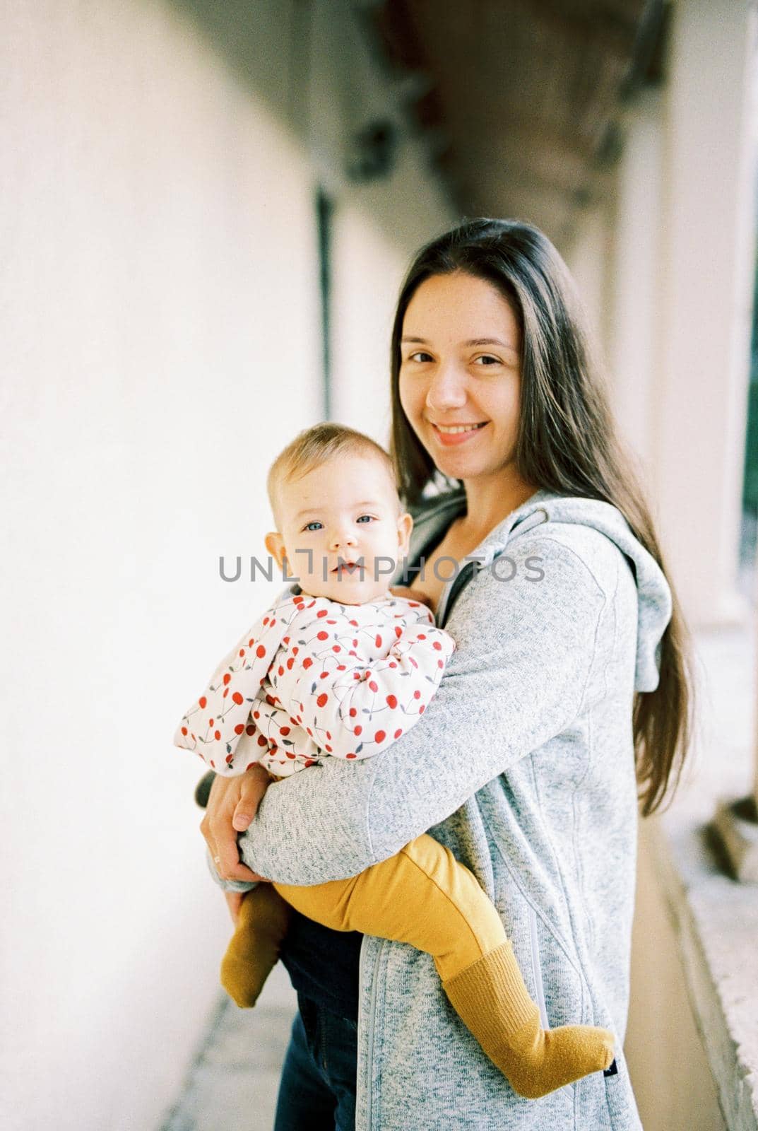 Smiling mom with a baby in her arms on the terrace. High quality photo