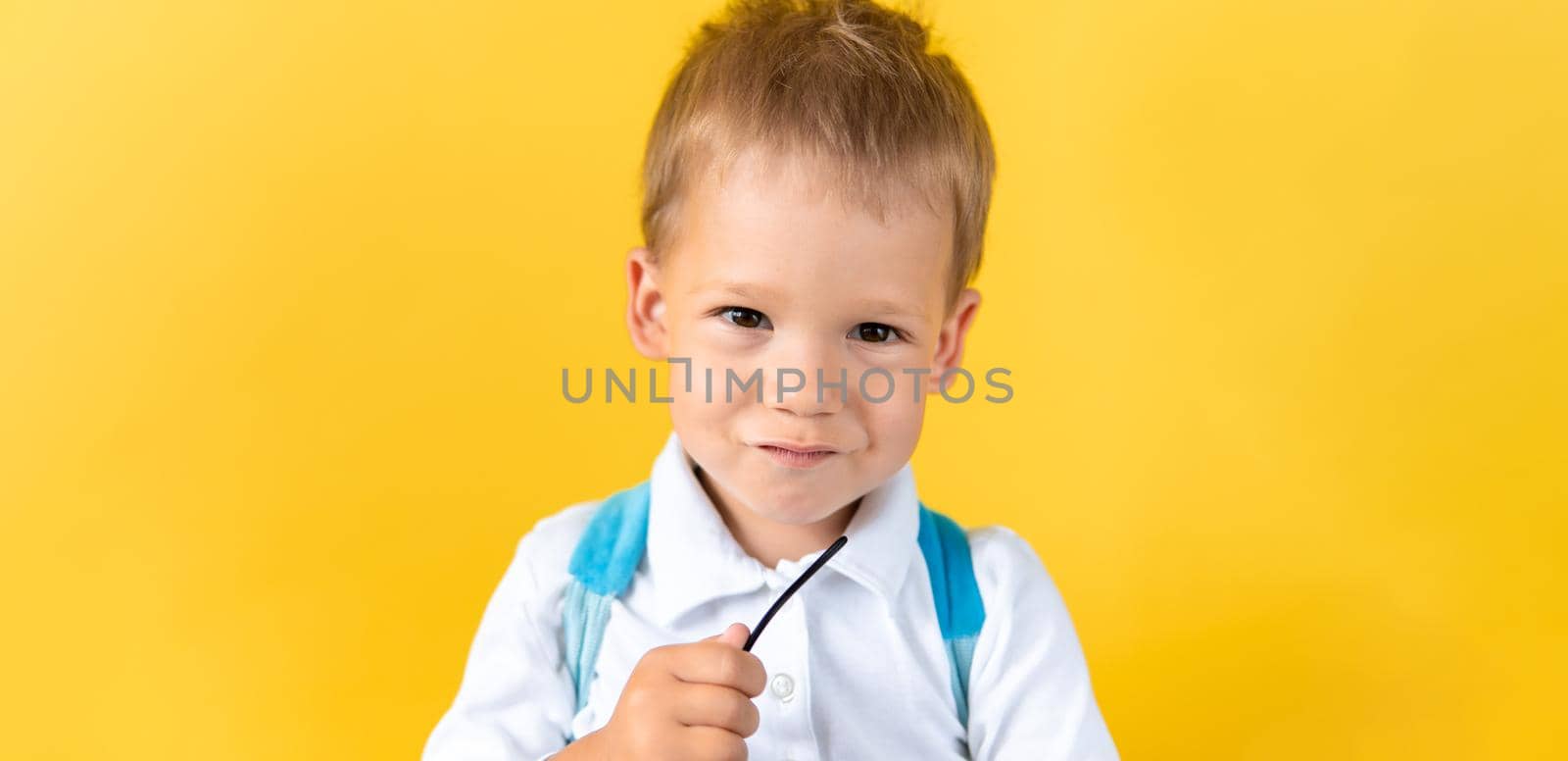 Banner Funny Preschool Child Boy smiles and looks slyly at camera on Yellow Background Copy Space. Happy Smiling Kid Go Back to School, Kindergarten. Success, Motivation, Genius, Superhero concept.