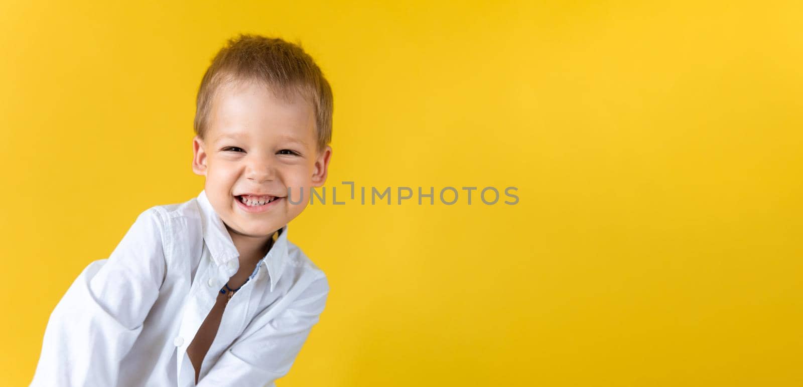 Banner Funny Preschool Child Boy in unbuttoned shirt smile narrow eye on Yellow Background Copy Space. Happy Smiling Kid Go Back to School, Kindergarten. Success, Motivation, Genius, Superhero concept.