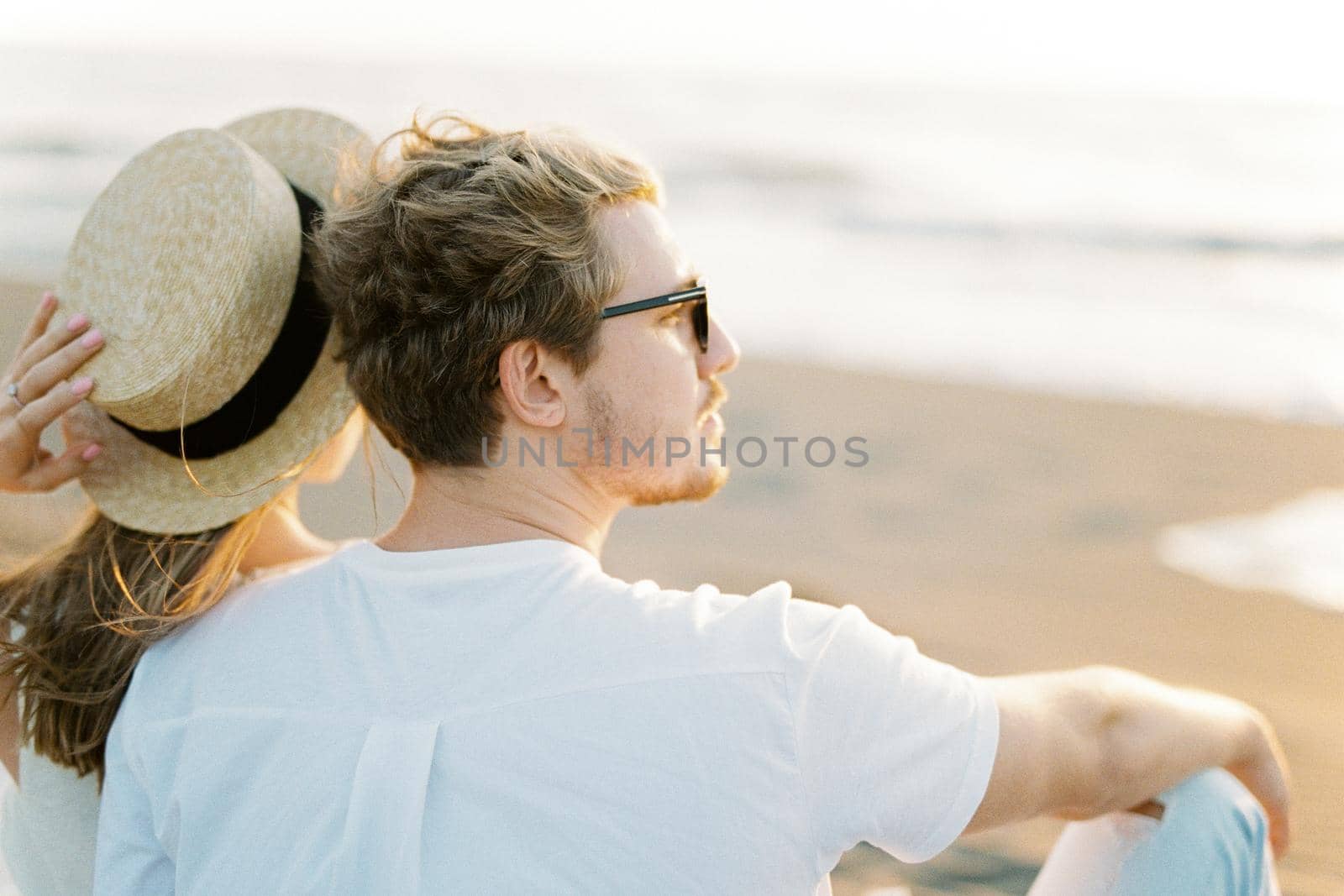 Woman sits on the sand leaning against a man. High quality photo