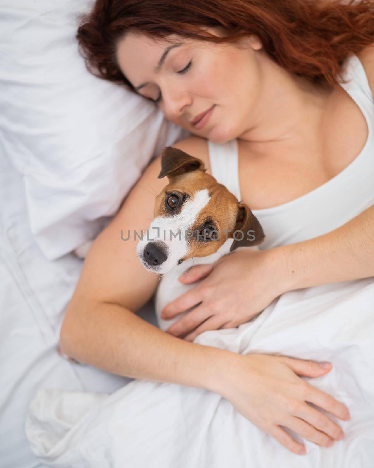 Caucasian woman is napping in bed hugging her beloved dog. by mrwed54