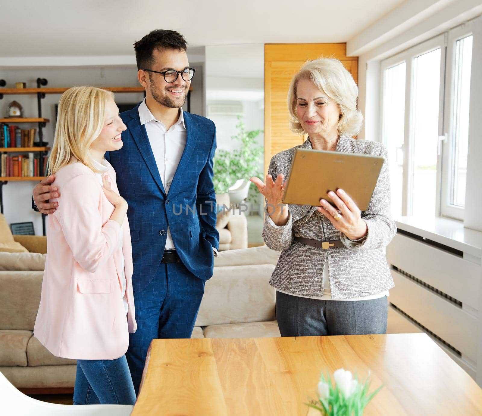 Young happy couple and an agent in a new property