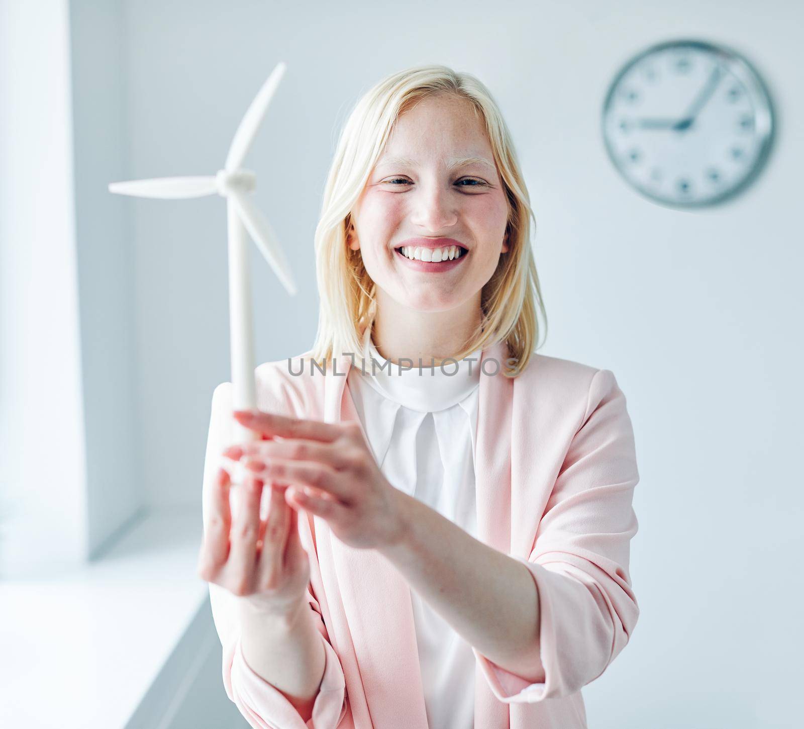 portrait of a young business woman holding a windmill model in the office
