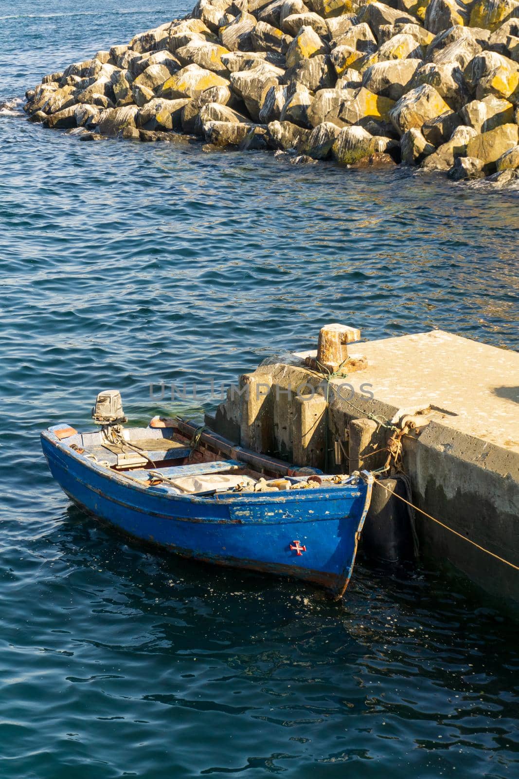 Old blue wooden boat moored at the pier top view on a sunny day