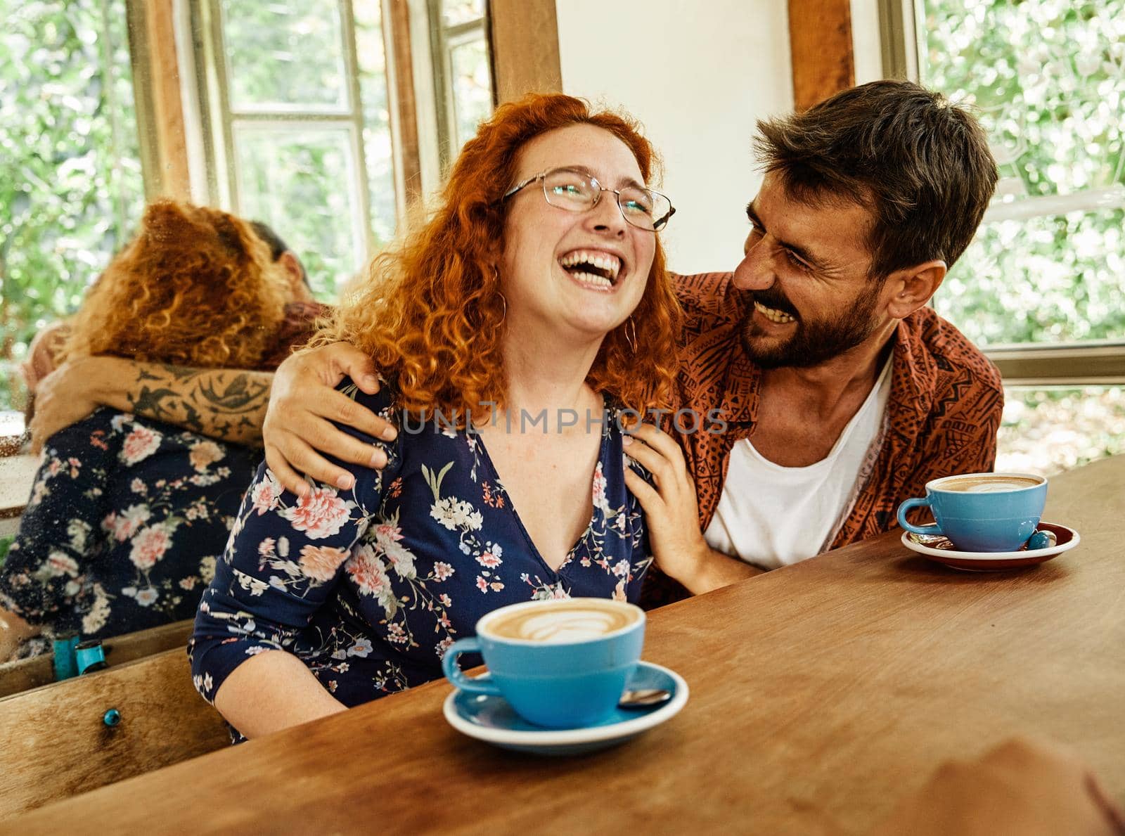 Happy young couple smiling and talking in a coffee shop cafe