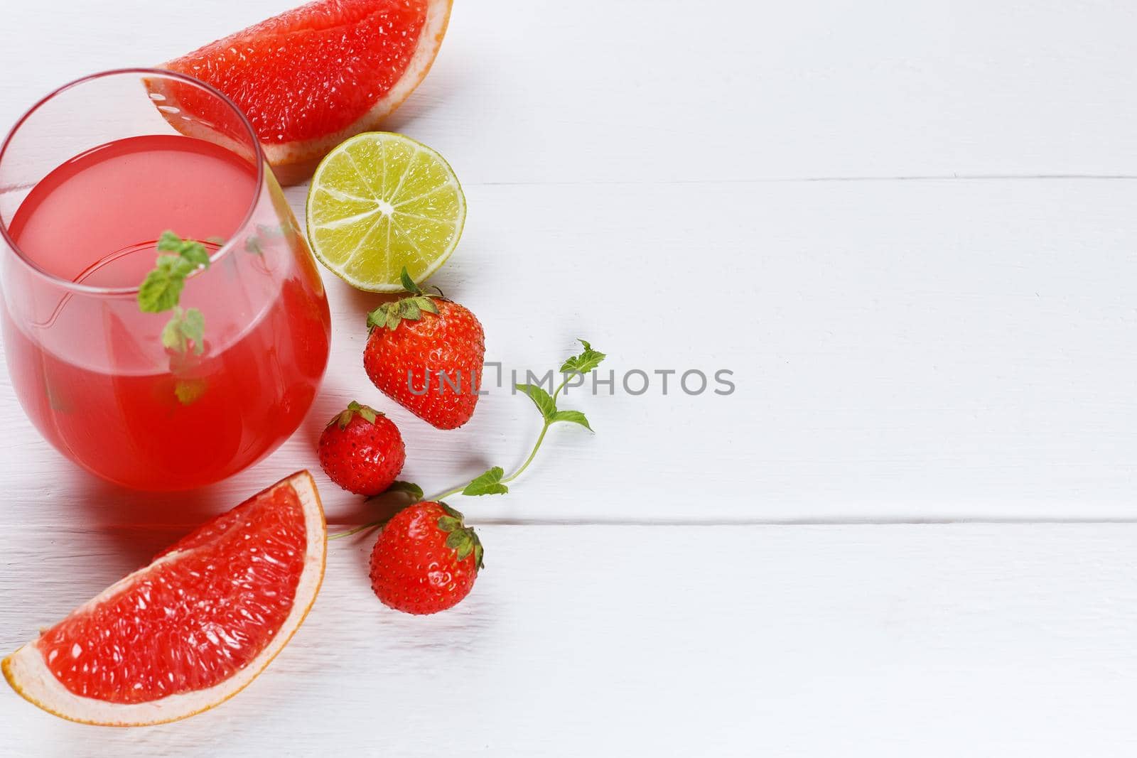 Fresh grapefruit juice in a glass with grapefruit slices, lime and mint on a wooden background. Copy space, selective focus by lara29