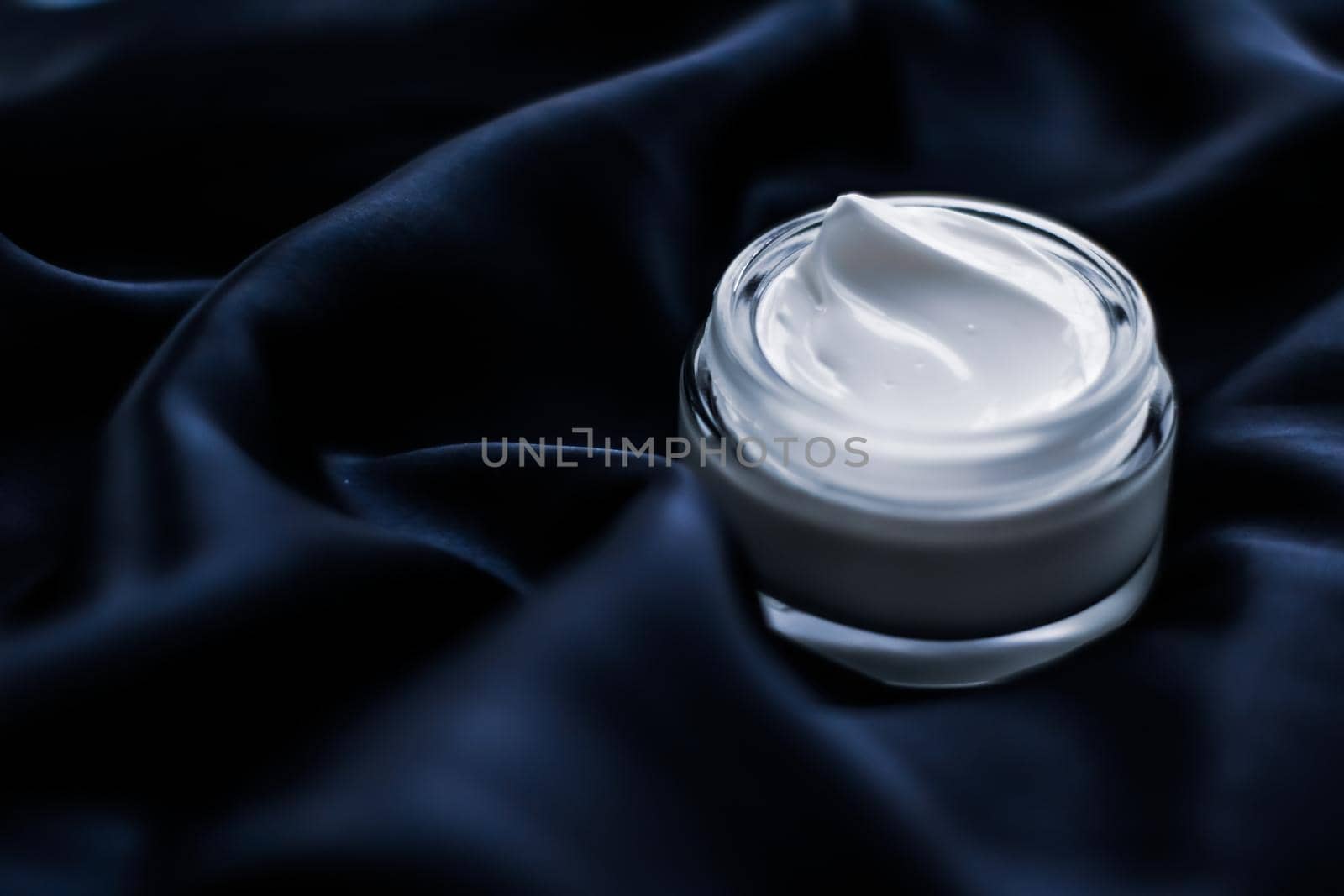 Beauty, anti-age cosmetics and skincare concept - Luxury face cream jar on a dark blue silk